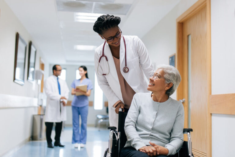 Female doctor pushing senior patient on wheelchair