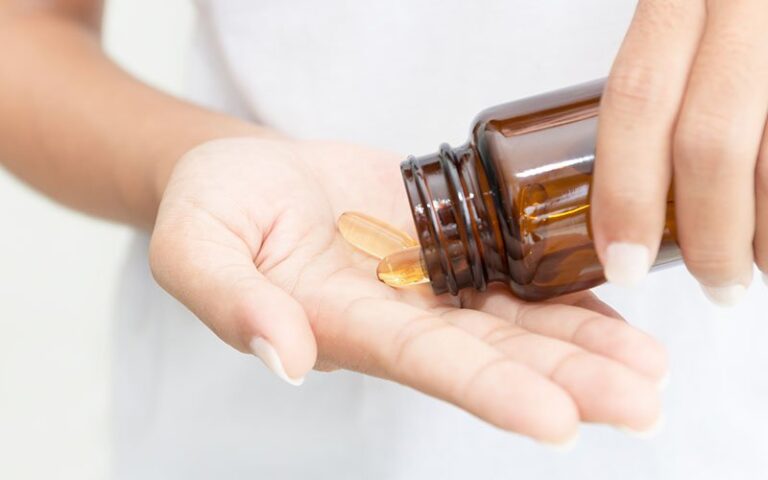 closeup hand holding fish oil vitamin for healthy