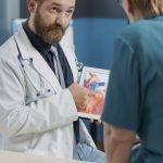 General practitioner holding tablet with heart condition